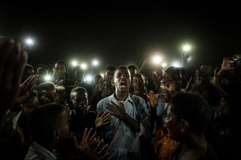Pressebild des Jahres 2020 von Yasuyoshi Ciba: Das Fotozeigt einen jungen Mann im Sudan, der Protestpoesie und dabei von Mobiltelefonen beleuchtet wird.